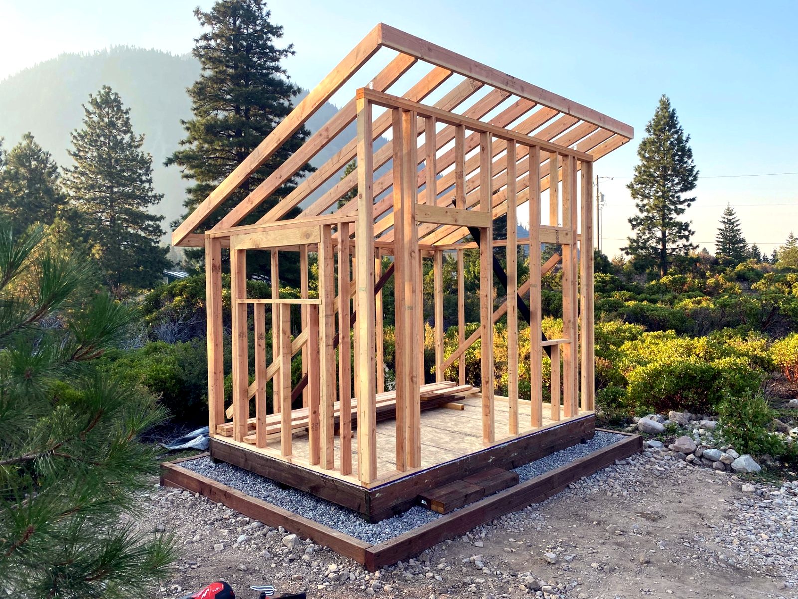 Wood-framed shed with a sloped roof on a gravel base